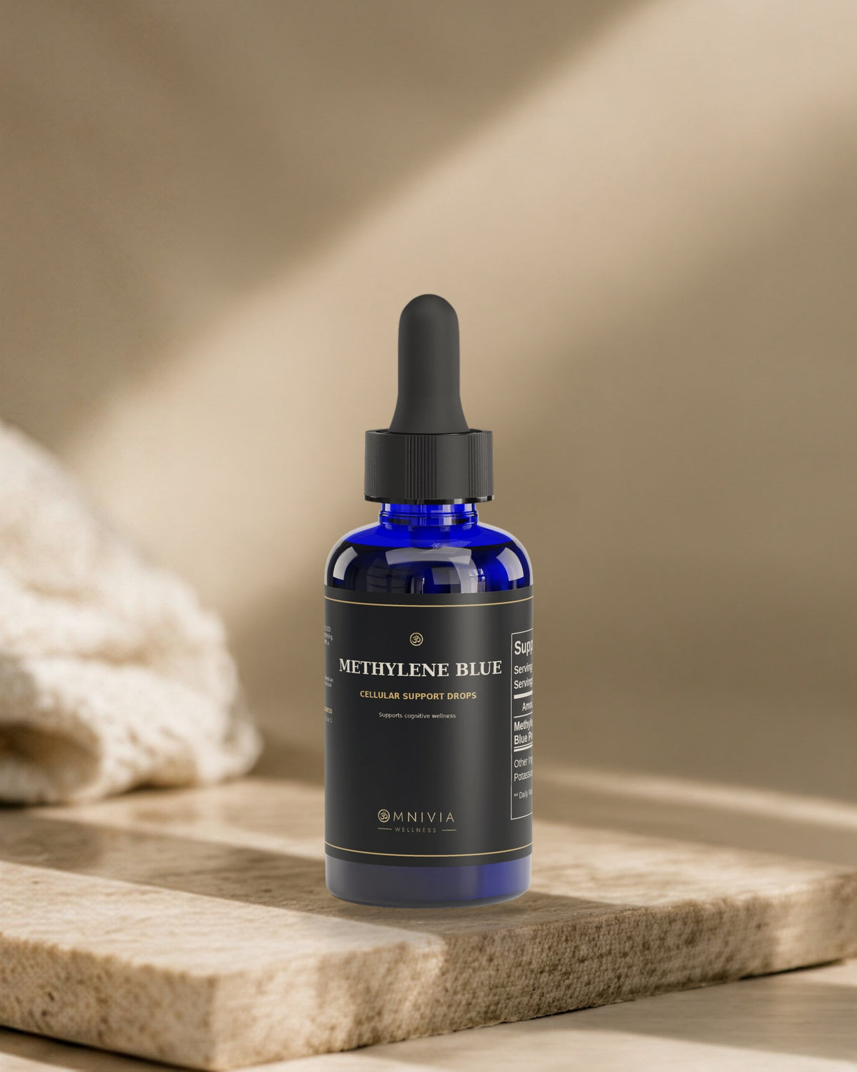 Omnivia Methylene Blue cobalt dropper bottle standing on a travertine slab in warm directional light