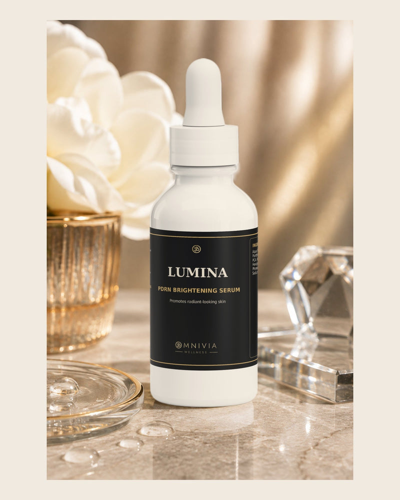 Lumina PDRN Brightening Serum dropper bottle beside white flowers and crystal on marble