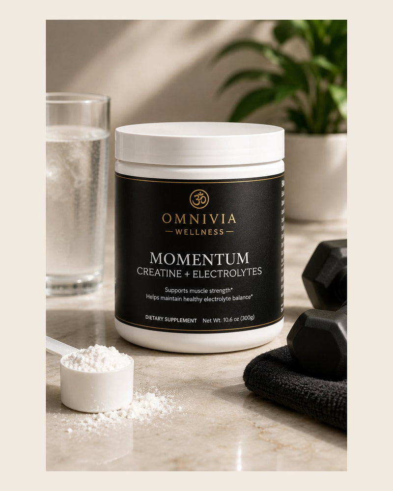 Momentum Creatine plus Electrolytes tub with a black and gold Omnivia Wellness label beside a scoop of powder and dumbbells